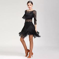 a woman in a short black dress with feathers on the skirt and heels is posing