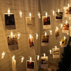 there are many pictures on the wall with lights strung from them and photos hung up