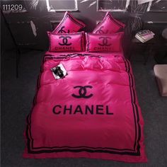 a chanel bed set with pink sheets and black lettering on the comforter is shown