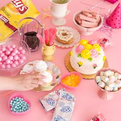 a pink table topped with lots of cakes and candy