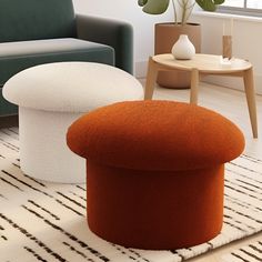 an orange ottoman sitting on top of a white rug next to a green chair and potted plant