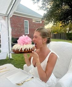 a woman sitting at a table with a cake in front of her and eating it