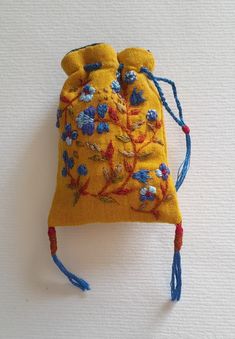 a small yellow pouch with blue flowers on the front and red string attached to it