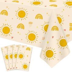 a table cloth with yellow sun designs on it and four napkins next to it