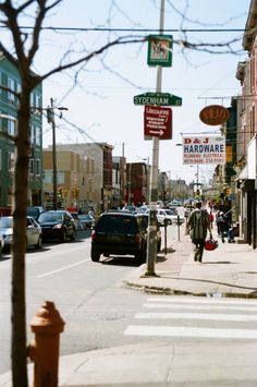 a city street with cars and people walking on the sidewalk