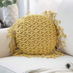 a yellow crocheted pillow sitting on top of a white couch