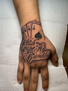 a person with a tattoo on their hand and playing cards in the middle of it