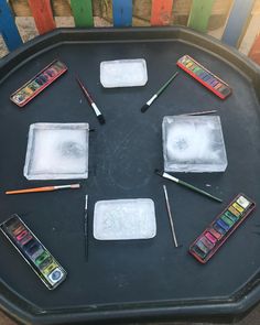 there are many different colored pencils and paints on the tray with ice cubes