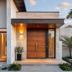 a modern house with wooden doors and plants in the front yard at sunset or dawn