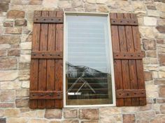 a window with wooden shutters on the side of a stone building