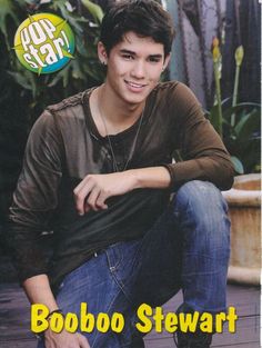 a young man sitting on the ground with his hand on his hip and smiling at the camera