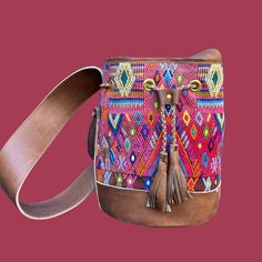 Score some style points with Intertwined's Small Huipil Bucket Bag! This dazzling piece is handcrafted with a vintage huipil (a traditional Mayan blouse) and vegetable-tanned leather. Its interior has a zip pocket and a slot pocket, perfect for stashing your phone, wallet, keys, and whatever else you need to bring along. And it's handmade by Guatemalan artisans at Cuero Malec. It's sure to get stares and questions from your pals - 'cause this bag is an absolute show-stealer! Artisan Bucket Bag With Leather Handles, Bohemian Hand-stitched Leather Bags, Leather Handwoven Shoulder Bag, Bohemian Pouch Bucket Bag With Leather Handles, Traditional Bucket Bag With Adjustable Strap For Everyday, Bohemian Multicolor Bucket Bag With Leather Handles, Traditional Bucket Bag With Leather Handles For Daily Use, Bohemian Leather Bucket Bag With Removable Pouch, Bohemian Shoulder Bag With Removable Pouch For Market