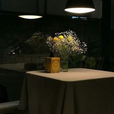 a vase with flowers on a table in a dark room next to a light fixture