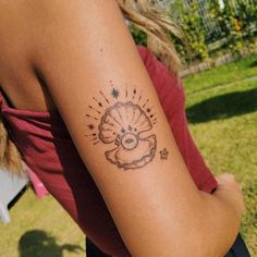 a woman's arm with a tattoo on it that has an image of a shell and stars