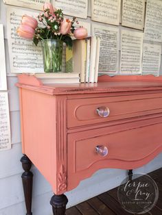 an old dresser is painted pink and has flowers in a vase on top of it