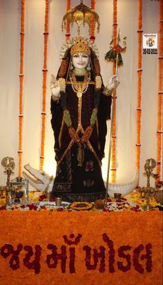 an idol is displayed in front of a backdrop with orange and white flowers on it