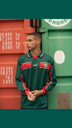 a young man standing in front of a green shipping container with numbers on the side