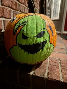 a pumpkin with a face painted on it sitting in front of a brick wall next to a door