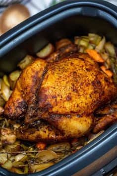 a close up of a chicken in a slow cooker with potatoes and carrots