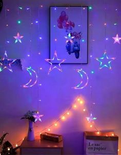 stars and moon lights hanging from the ceiling in a room with purple lighting on it