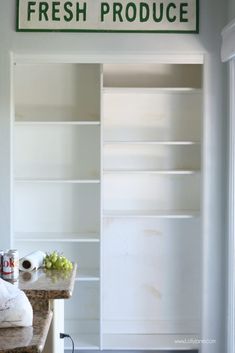 a fresh produce store sign hanging from the side of a white bookcase filled with books