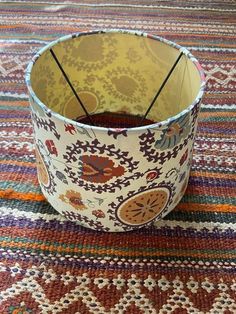 a lamp shade sitting on top of a colorful rug next to a wooden stick holder