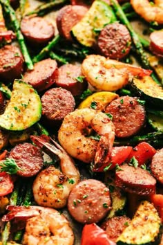 a sheet pan filled with sausage, shrimp and asparagus on top of it