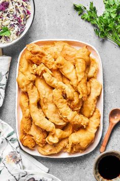 fried chicken in a white dish next to a bowl of coleslaw