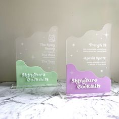 two glass plaques sitting on top of a marble counter next to each other, with the words signature cocktails