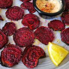 beet chips on a plate with dipping sauce and lemon wedges next to them