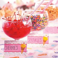 cherries are in small bowls on a table with candy and sprinkles