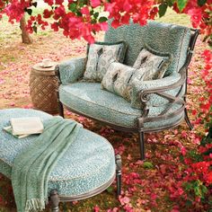 two chairs and a table in the middle of some bushes with flowers around them,