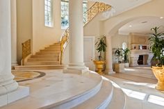 a large foyer with white marble steps and gold planters on either side of the staircase