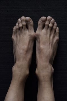 two bare hands are shown in the middle of this photo, with one person's feet on the ground