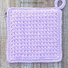 a crocheted square with a hook in the middle on a wooden background that says,