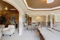 a living room filled with furniture and a pool table in front of a bar area