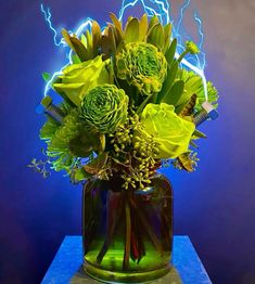 a vase filled with yellow flowers on top of a blue table next to a wall