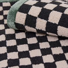 black and white checkered rugs with green trim on them are laying next to each other