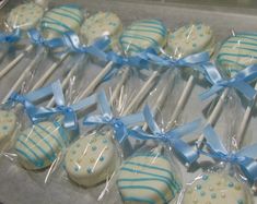 blue and white cake pops are on display in plastic wrappers with bowknots