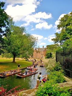 many people are on boats in the water near a fence and trees with green leaves