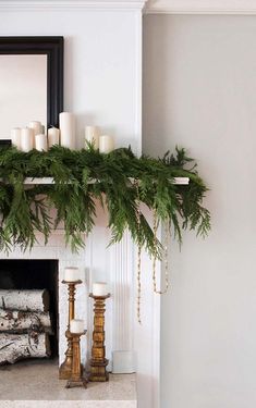 a mantel with candles and greenery on it