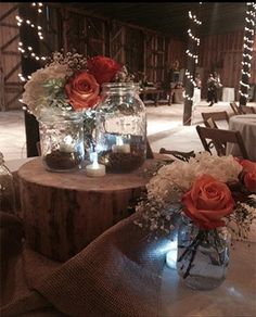 two vases filled with flowers sitting on top of a wooden table covered in lights