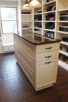 a walk in closet with lots of shoes on the floor and shelves full of shoes