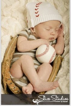 a baby laying in a baseball mitt holding a ball