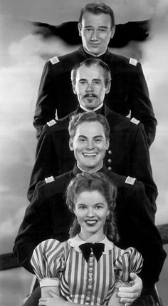 an old black and white photo of four people in uniform, with one man standing on top of the woman's head