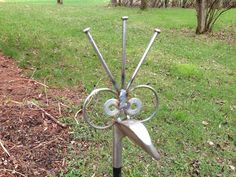 there is a metal sculpture in the grass with four knives sticking out of it's center