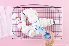 a person is holding an item in front of a wire rack with white gloves on it