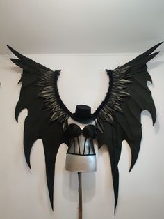 a hat is sitting on top of a mannequin with large black wings attached to it