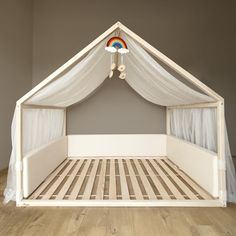 a bed with a white canopy over it on top of a hard wood floor in a room