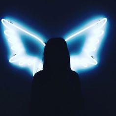 a woman standing in front of a neon butterfly